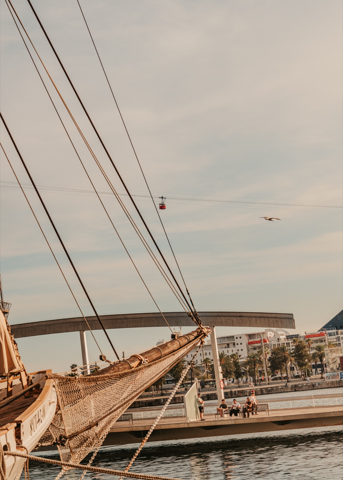 The bow and rigging of a wooden sailing ship, with the cable car and a gull in the sky above